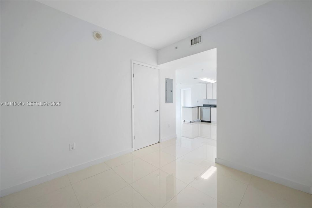 Neutral interior featuring polished large-format tile flooring, white wall finishes, and a solid-core interior door