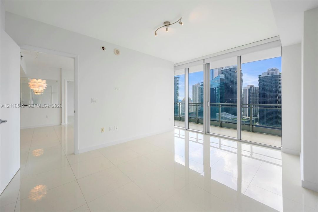 Interior space featuring floor-to-ceiling windows, polished tile flooring, a balcony with a metal railing, and adjustable multi-bulb ceiling lighting