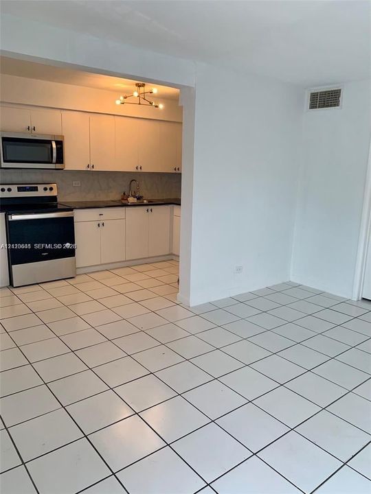 Kitchen featuring white cabinetry, dark countertops, a stainless steel range and microwave, and ceramic tile flooring