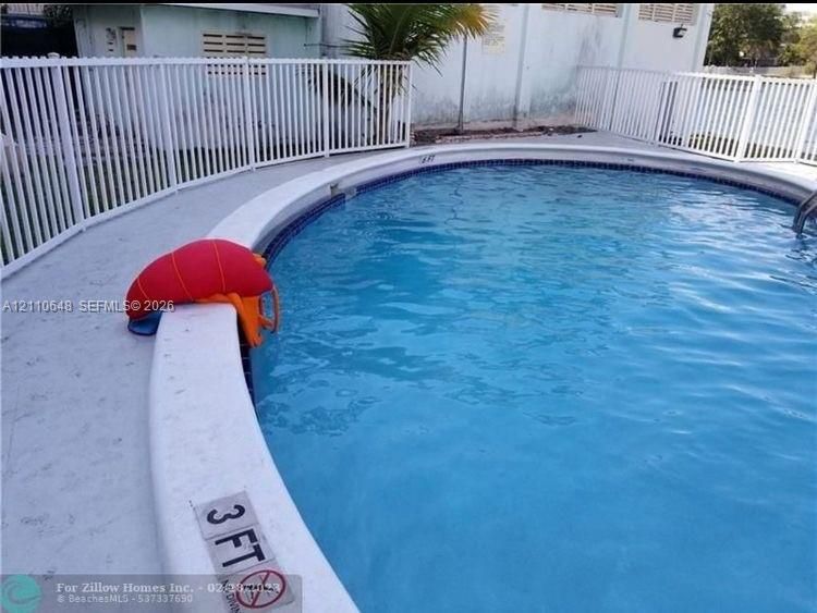 Circular swimming pool featuring a concrete deck and white aluminum perimeter fencing