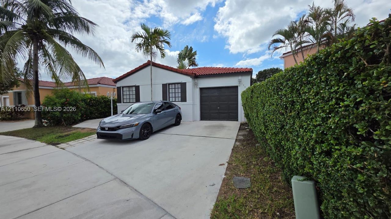 Stucco exterior featuring a red tile roof, single-car garage, and concrete driveway