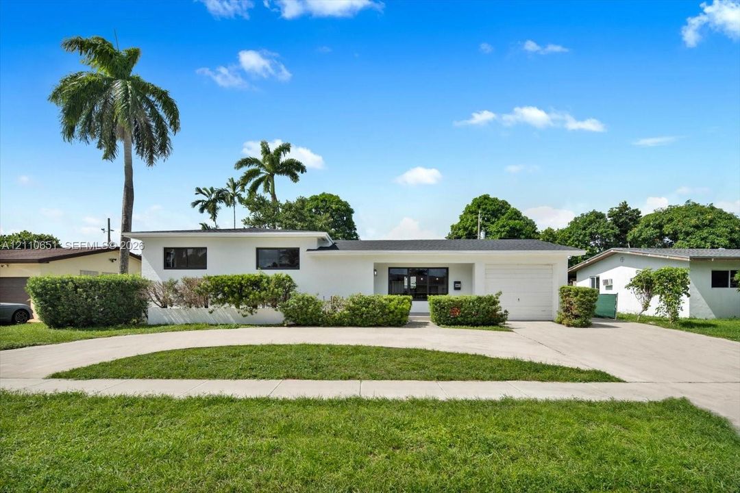 Single-story residence featuring a low-slope roof, white exterior cladding, single-car garage, and a concrete semi-circular driveway