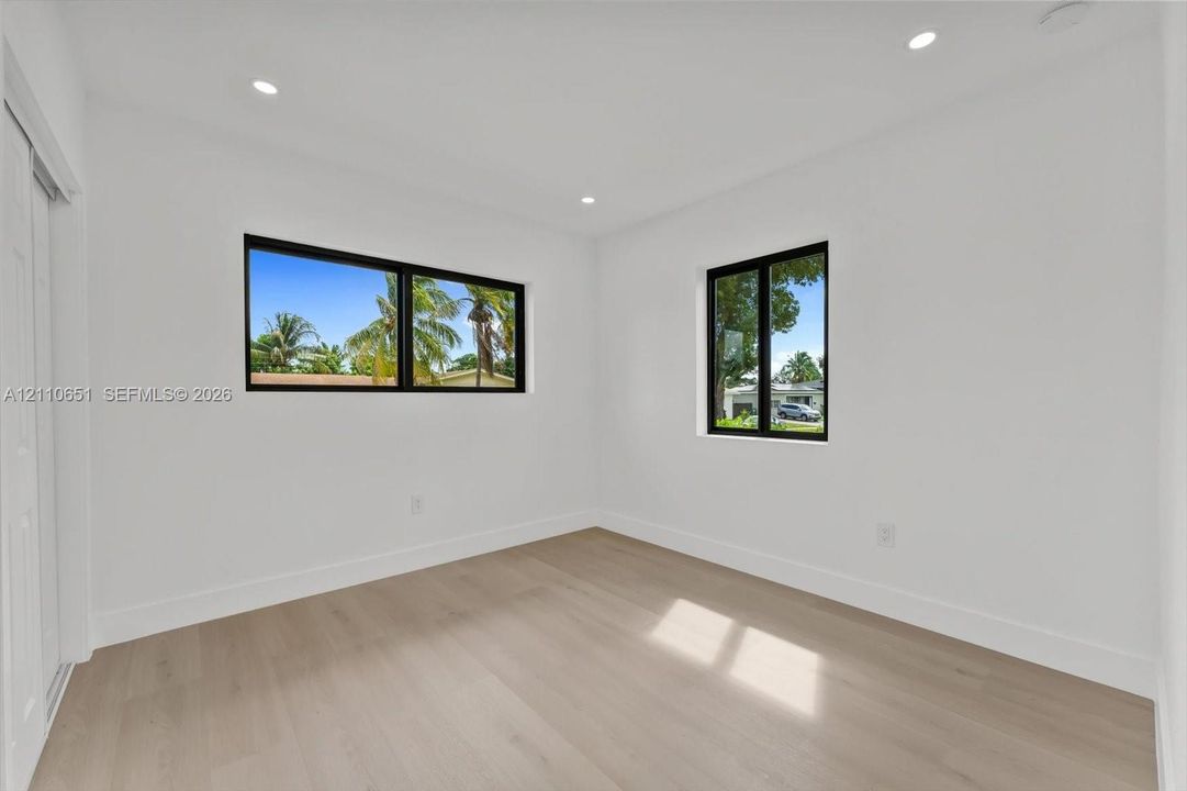 Bright interior featuring light-tone wood-finish flooring, recessed lighting, and black-framed windows