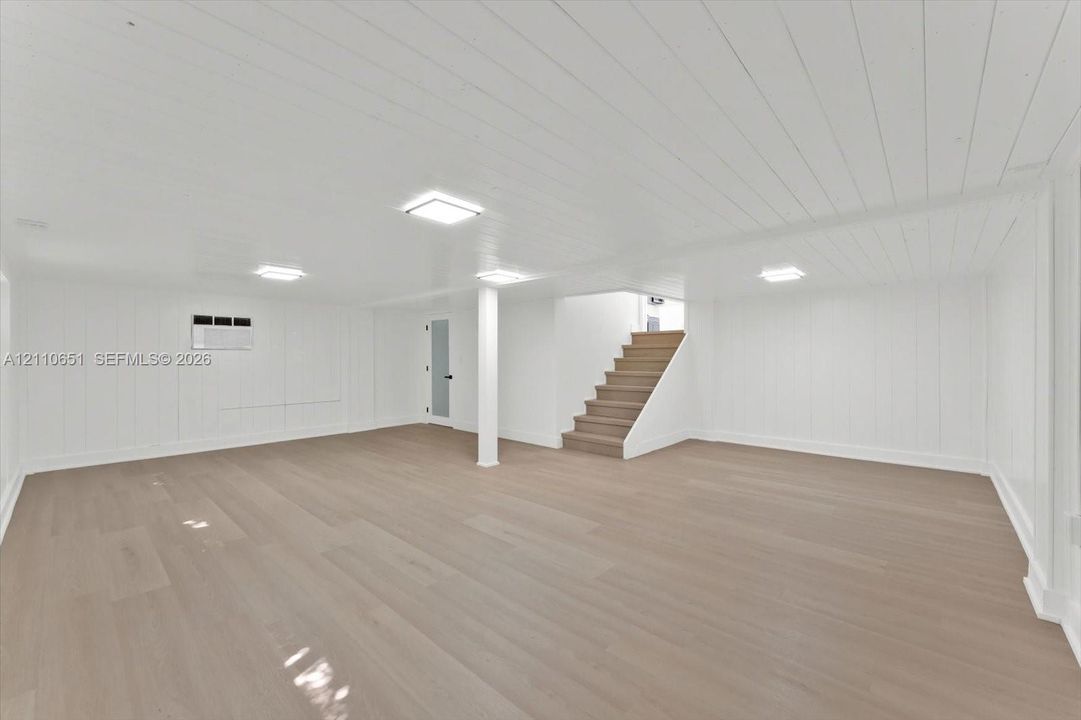 Finished interior space featuring wood-finish flooring, tongue-and-groove ceiling paneling, recessed lighting, and carpeted staircase