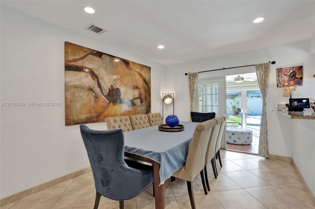 Neutral tile flooring, recessed lighting, and a glass-paneled sliding door providing exterior access