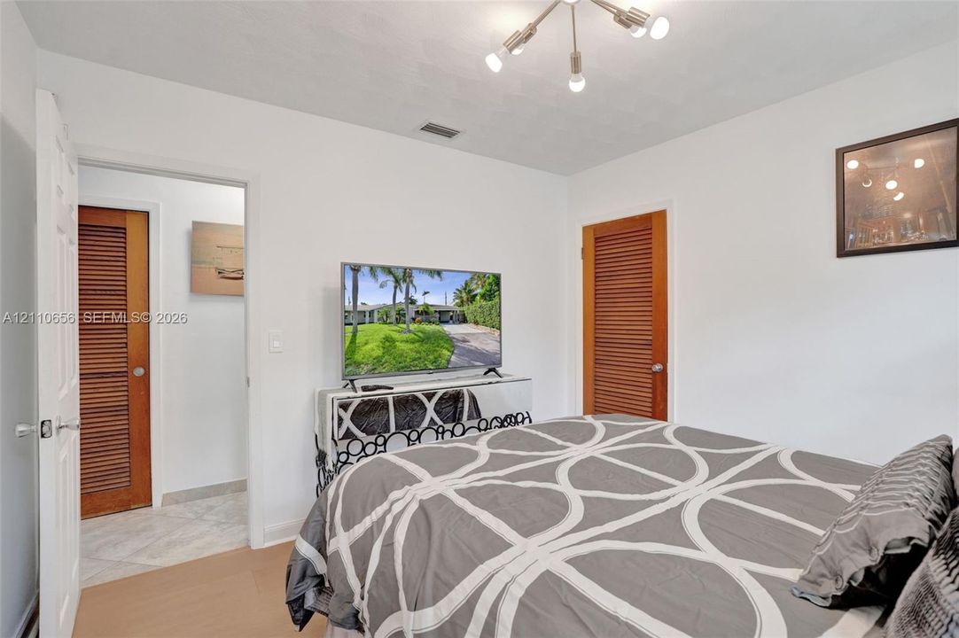 Neutral interior featuring wood-finish flooring, a multi-arm modern light fixture, and dual wood-tone louvered doors