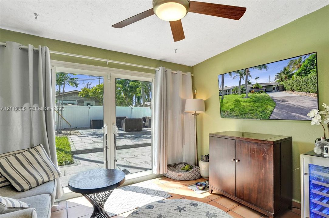 Double glass patio doors featuring white frames, ceiling fan with light fixture, and tile flooring