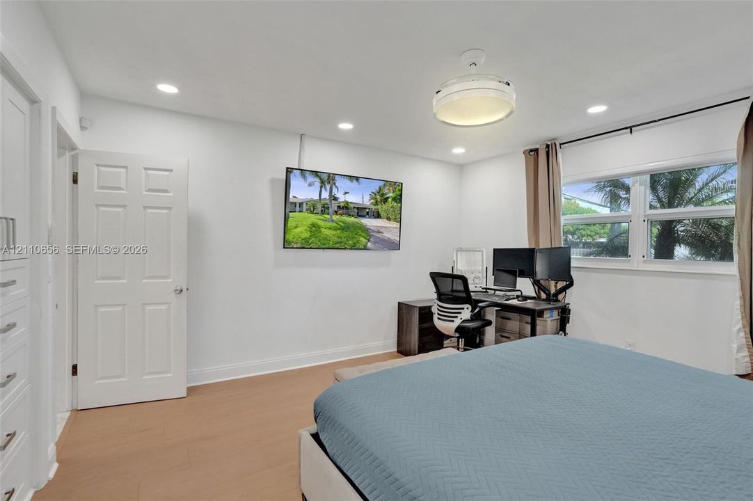 Room featuring wood-finish flooring, recessed lighting, a modern ceiling fixture, and a built-in cabinet