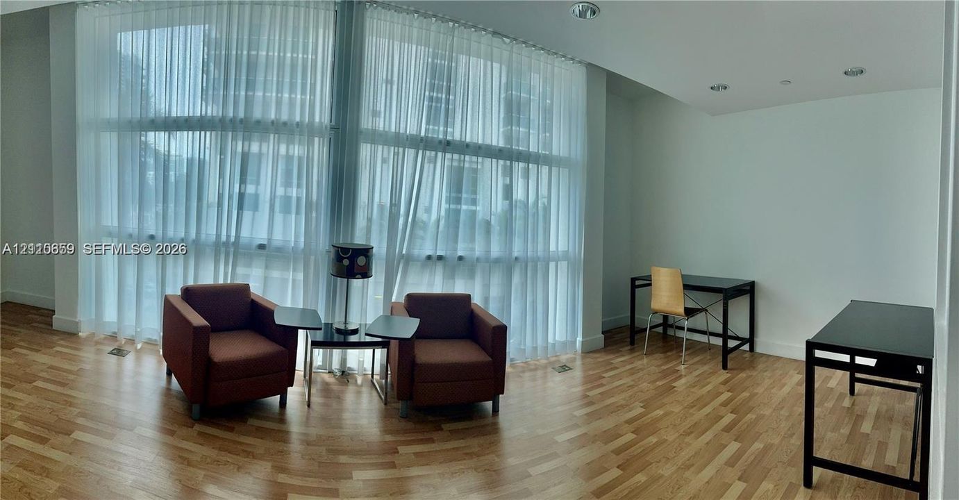 Floor-to-ceiling windows with full-height drapery, wood-finish flooring, and recessed ceiling lighting