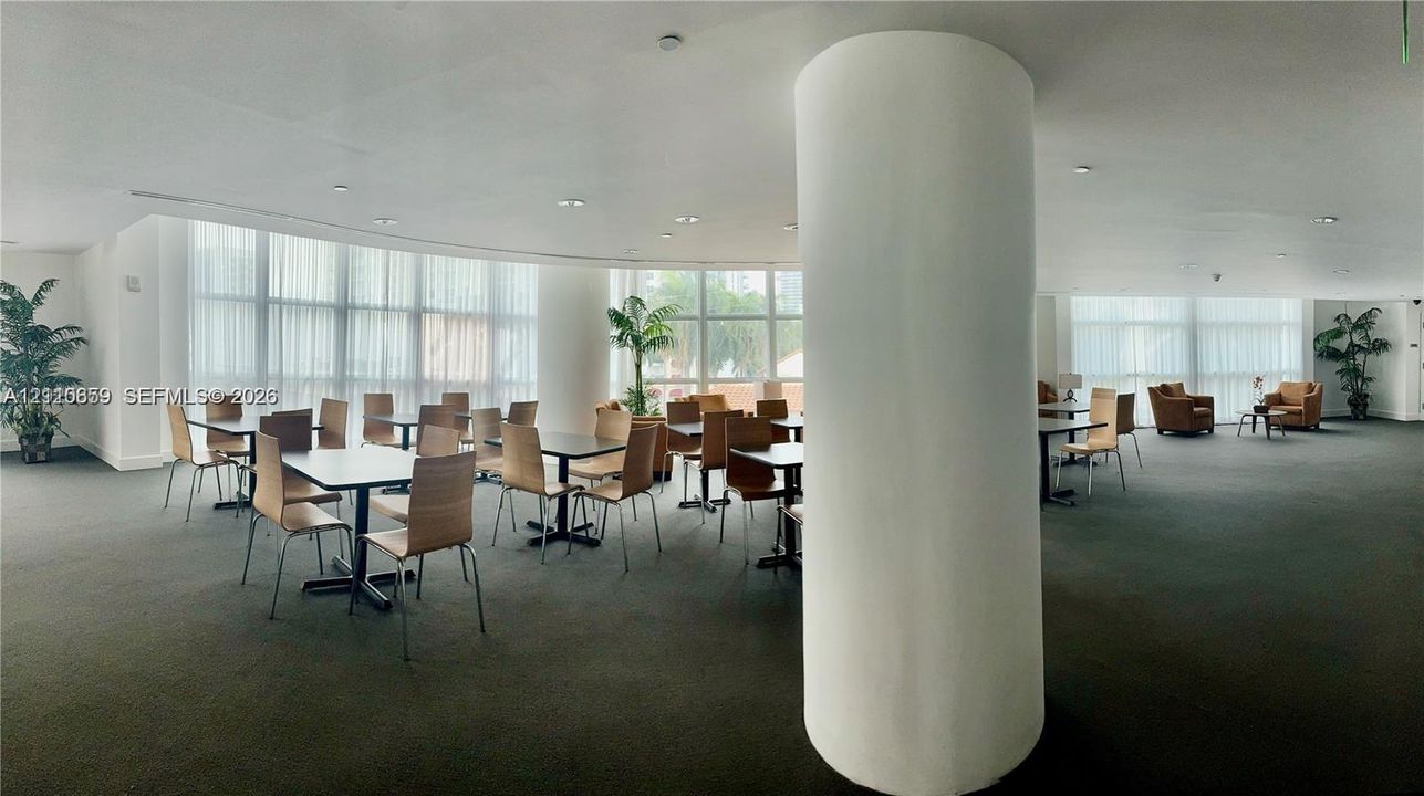 Expansive open-concept room featuring floor-to-ceiling windows, recessed lighting, and a prominent cylindrical architectural column