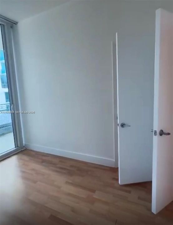 Floor-to-ceiling glass panel, wood-finish flooring, and crisp white interior paint, featuring hinged doors with brushed metal hardware