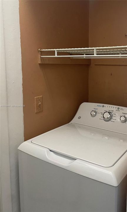 Utility space featuring a white top-load washer and a built-in wire shelving unit