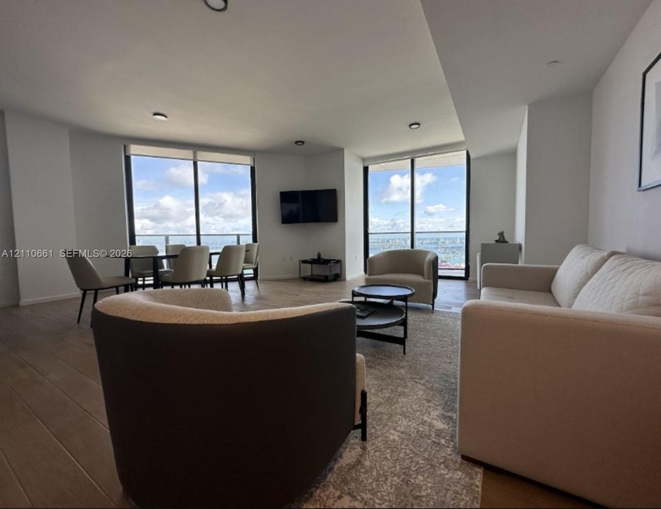 Open-concept living space featuring wood-finish flooring, floor-to-ceiling windows, and private balcony access
