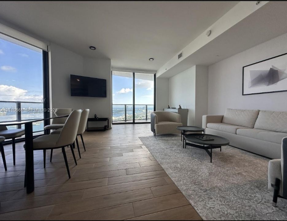 Open-concept living space featuring floor-to-ceiling glass walls, wood-finish tile flooring, and recessed lighting