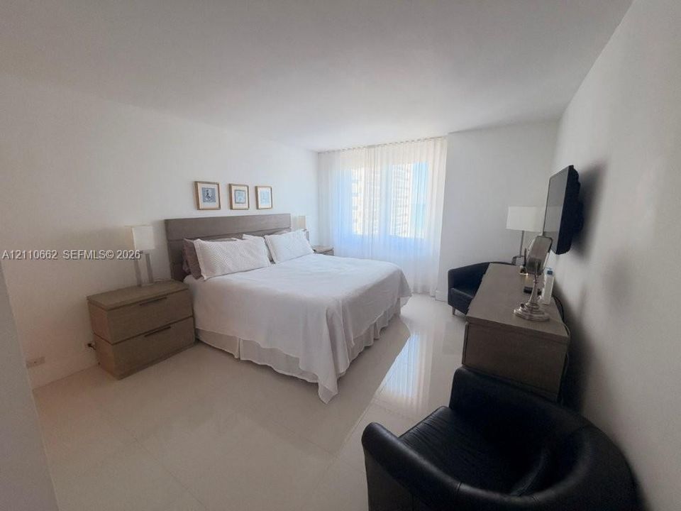 Spacious room featuring polished neutral flooring, a wall-to-wall window treatment, and crisp white wall finishes