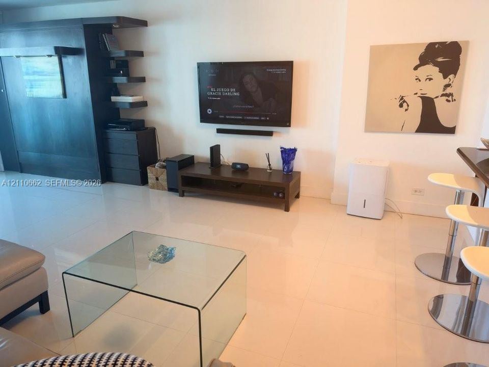 Large-format tile flooring, built-in dark wood-finish cabinetry with open shelving, and neutral wall tones