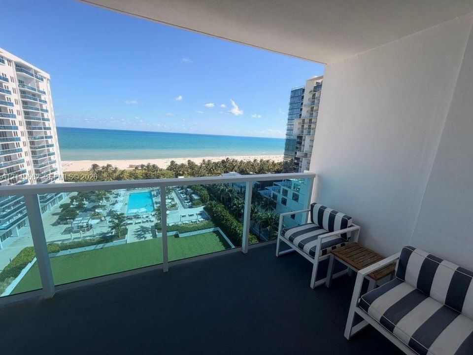 Covered balcony featuring a glass panel railing and open-air access to coastal scenery