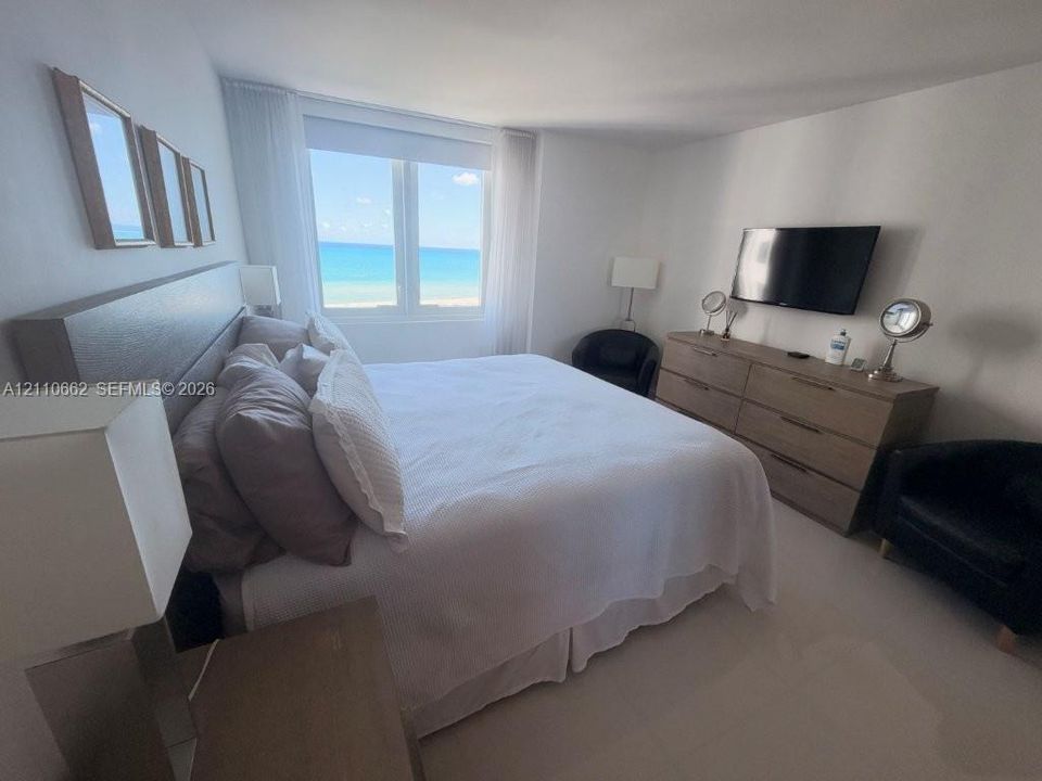 Large picture window with ocean backdrop, light-toned tile flooring, and neutral wall finishes