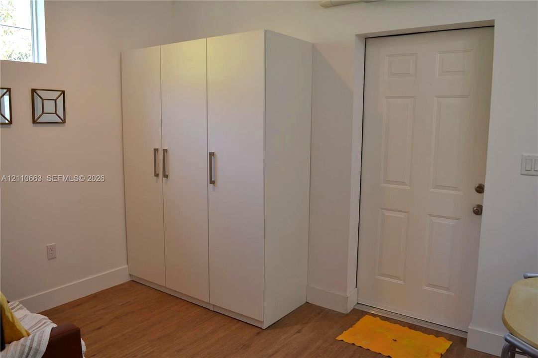 Built-in floor-to-ceiling cabinetry with brushed metal hardware, wood-finish flooring, and a solid six-panel door