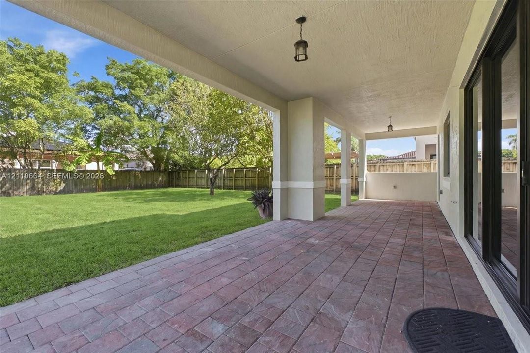 Spacious covered patio with paver flooring, opening to a fully fenced backyard with ample room for a custom pool and an expansive outdoor entertaining retreat