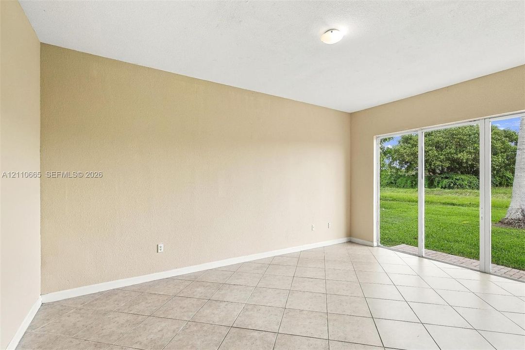 Neutral interior featuring large-format ceramic floor tile, textured wall surfaces, and a multi-panel sliding glass door providing external exposure