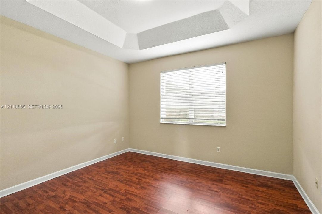 Tray ceiling, wood-finish flooring, and horizontal window blinds