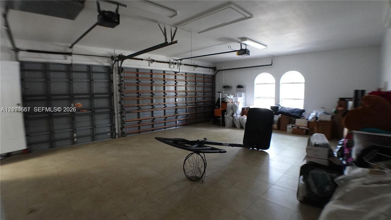 Multi-car garage featuring segmented metal overhead doors, overhead lighting fixtures, and arched windows