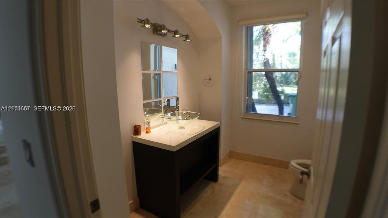 Bathroom featuring a vanity with an integrated basin, multi-pane wall mirror, light fixture, and stone-finish flooring
