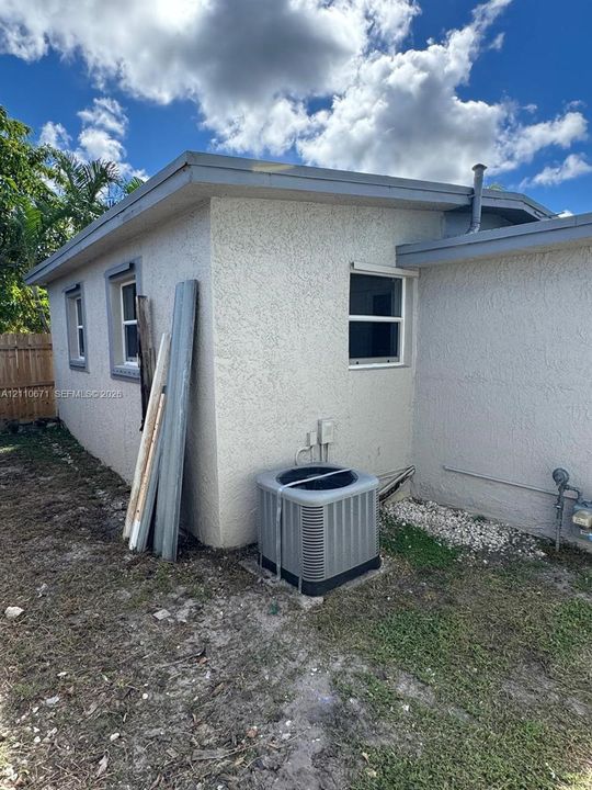 Stucco exterior featuring dual-pane windows, a roof-mounted plumbing stack, and a central air conditioning condenser unit