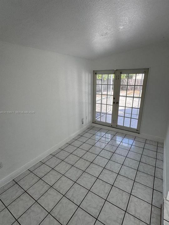 Interior space featuring neutral wall tones, ceramic tile flooring, and glass-paned French doors with an exterior patio