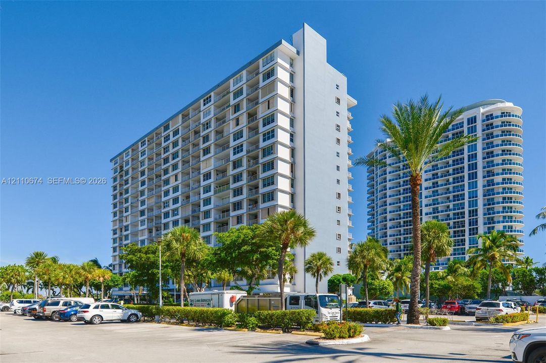 High-rise exterior featuring a multi-story concrete facade with integrated private balconies and floor-to-ceiling glass paneling