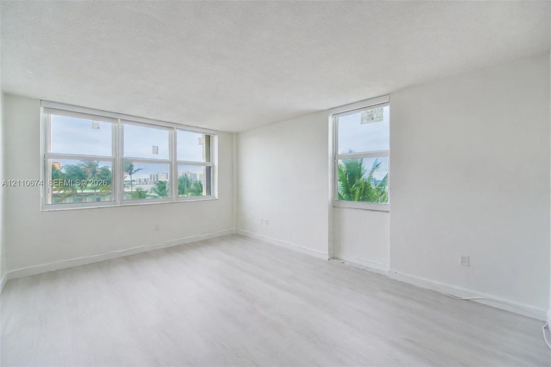 Interior space featuring light wood-finish flooring, neutral wall tones, and multiple large windows