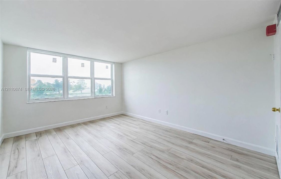 Interior room featuring wood-finish flooring, white walls, and large multi-pane windows