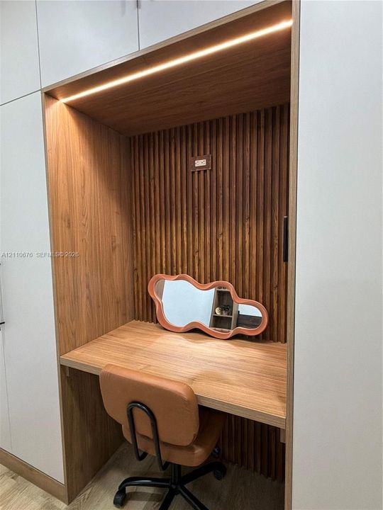 Built-in desk alcove featuring wood-finish cabinetry, vertical slat wall detailing, and integrated recessed accent lighting