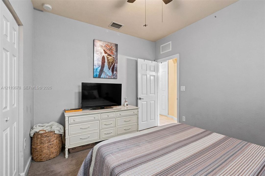 Neutral-toned room featuring plush wall-to-wall carpeting, a ceiling fan with integrated lighting, and a multi-panel interior door