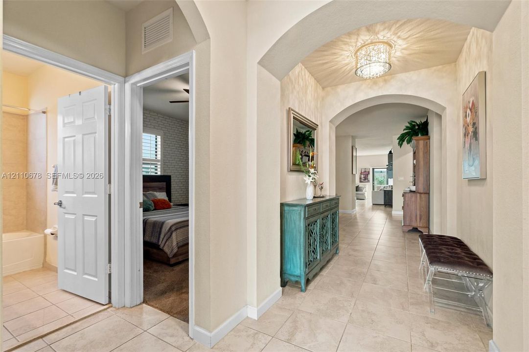 Interior hallway featuring tile flooring, arched architectural detailing, and a decorative flush-mount ceiling light fixture