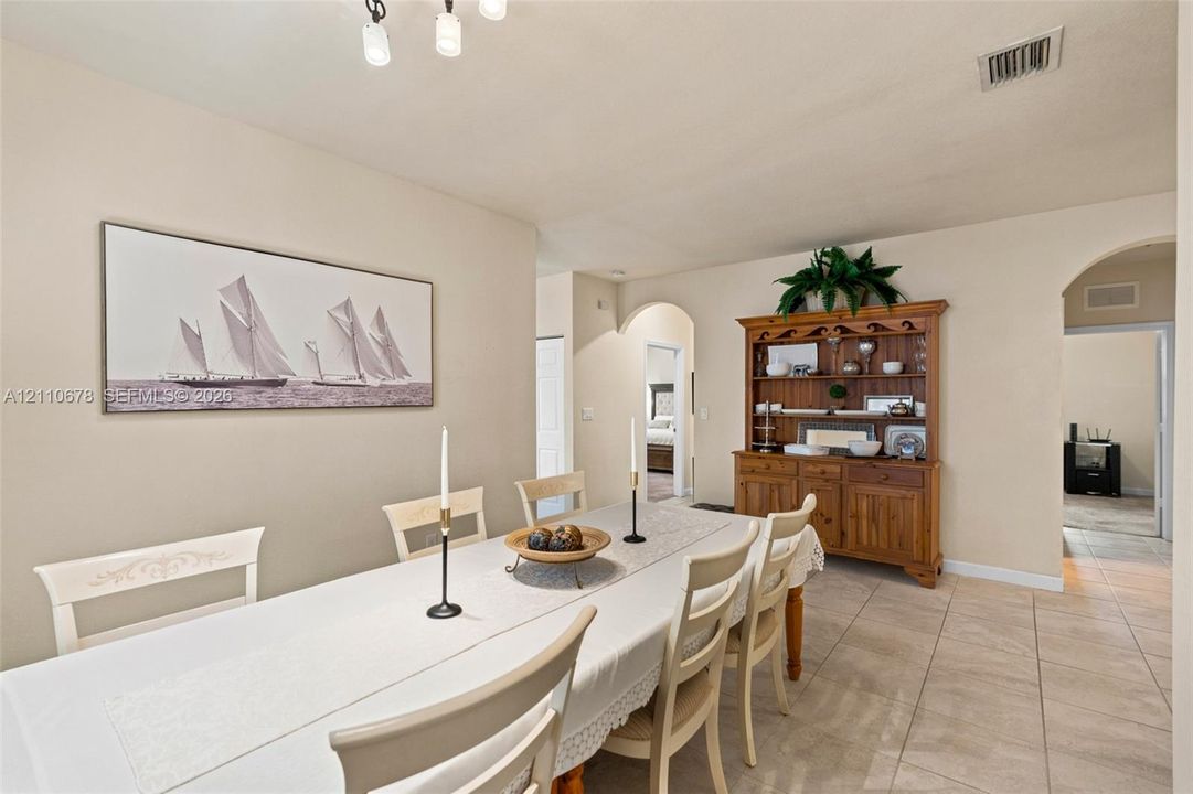 Dining area featuring ceramic tile flooring, neutral wall paint, arched entryways, and a multi-light flush-mount chandelier