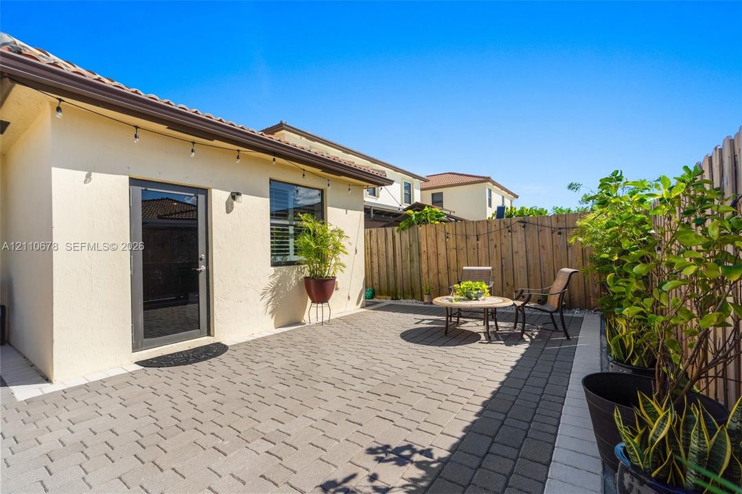 Private patio featuring light-toned paved hardscaping, a tile-roof structure, and an enclosed wood fence