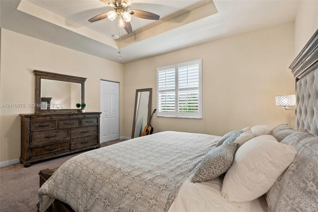 Tray ceiling, ceiling fan with light fixture, and window with plantation shutters