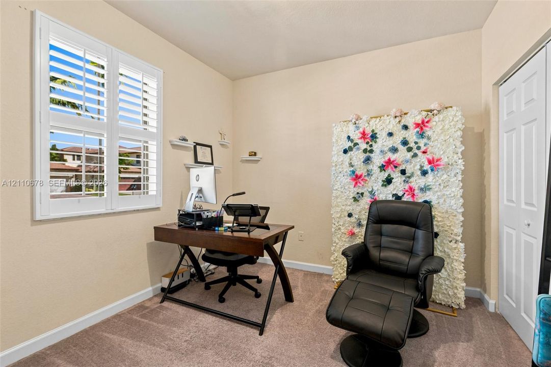 Interior room featuring neutral-toned carpeting, white plantation shutters, and a six-panel closet door
