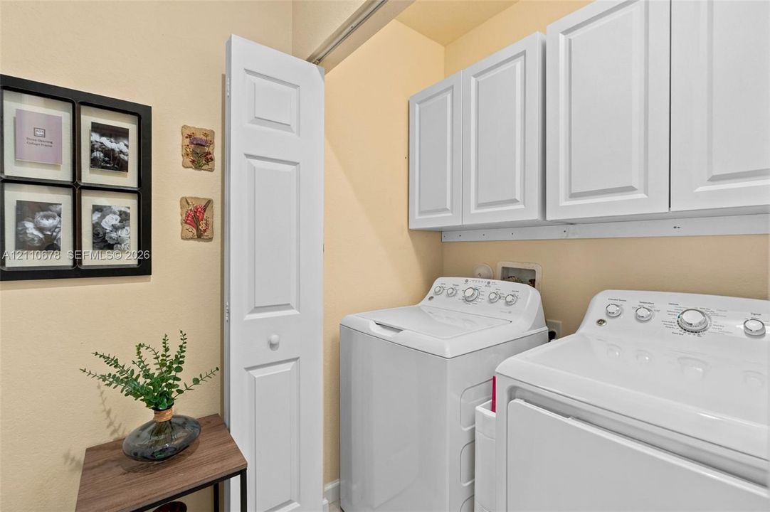 Laundry area featuring white shaker-style wall-mounted cabinetry and a white bifold door