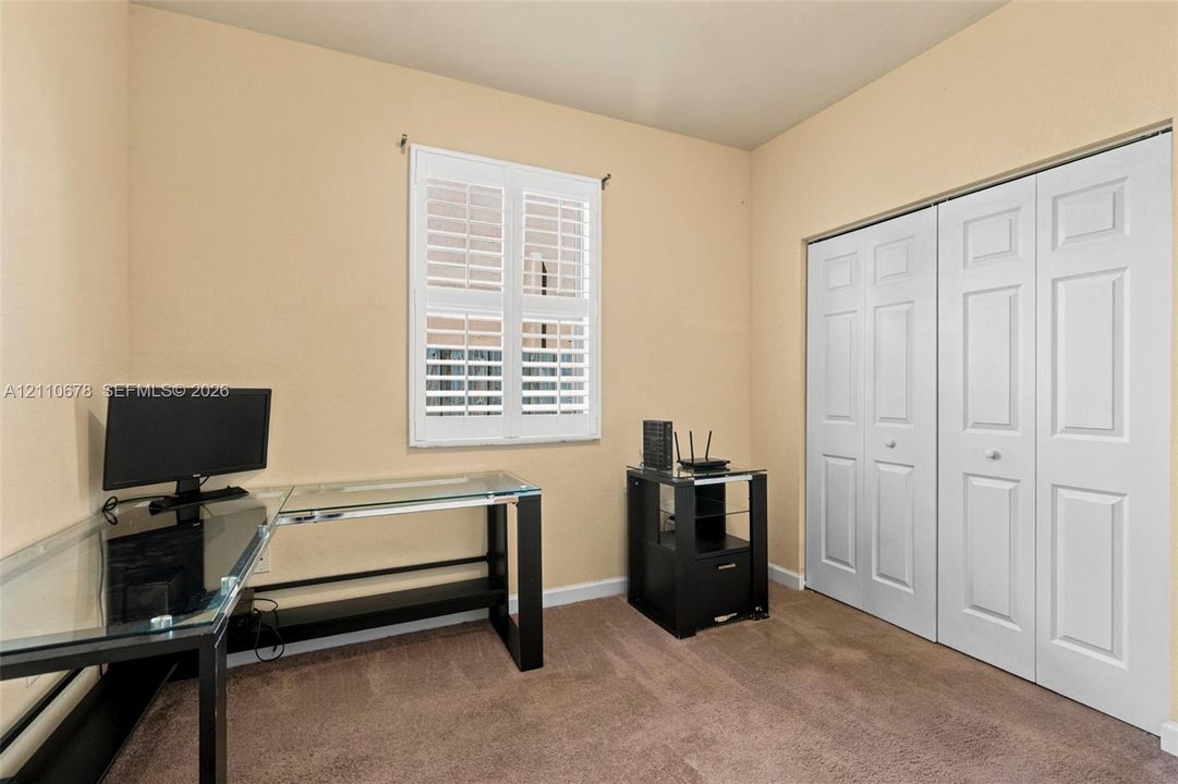 Room with wall-to-wall carpeting, white plantation shutters, and a double-door closet with paneled doors