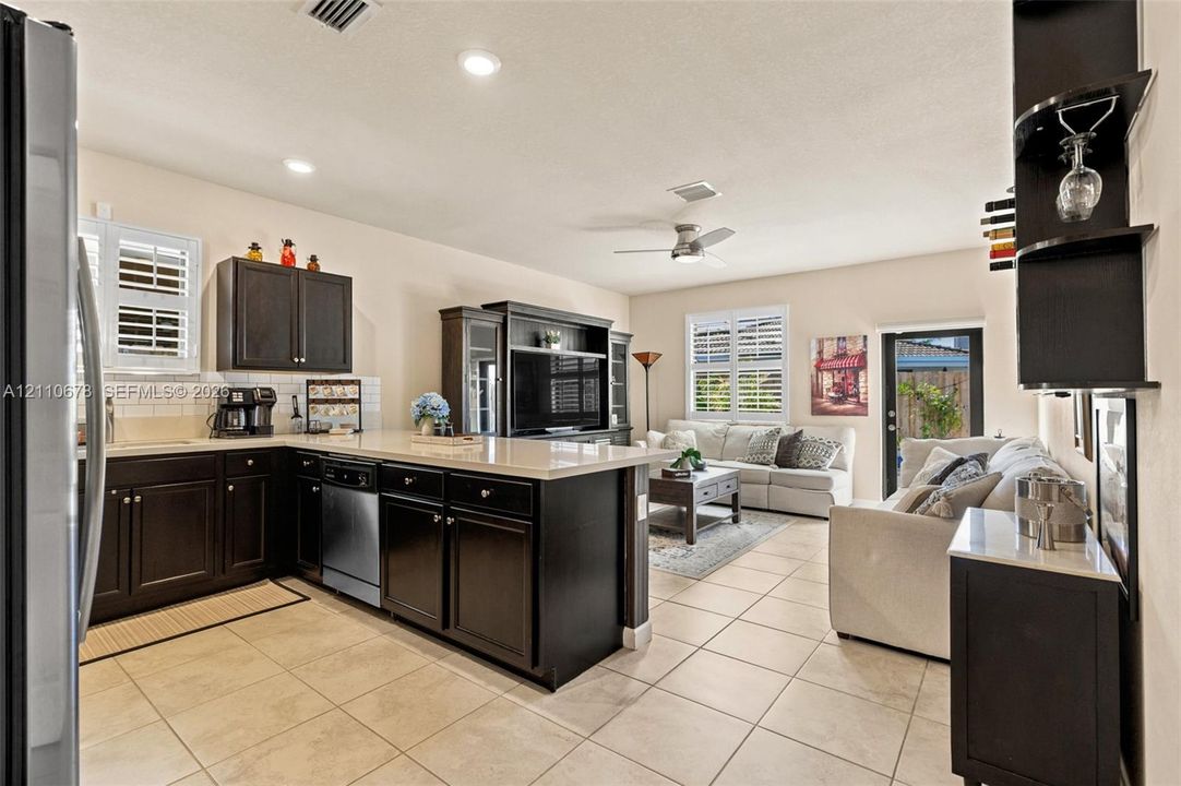 Kitchen featuring dark cabinetry, stone-surface countertops, subway tile backsplash, and stainless steel dishwasher