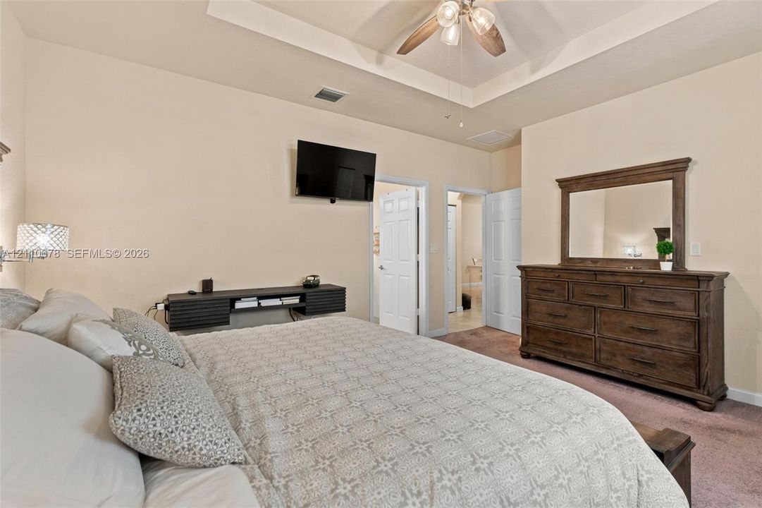 Tray ceiling featuring a central ceiling fan with integrated lighting and wall-mounted, built-in shelving