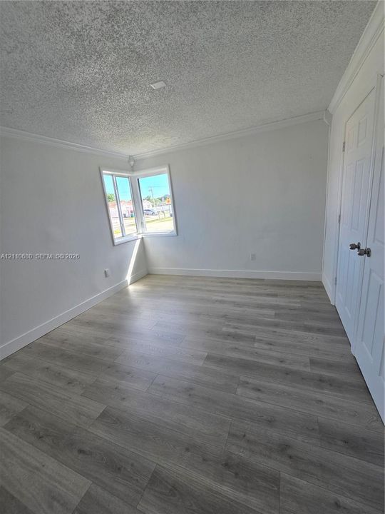Room featuring wood-finish flooring, corner window, and dual-panel closet doors