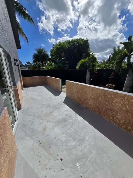 Concrete patio featuring tile-faced retaining walls and perimeter fencing