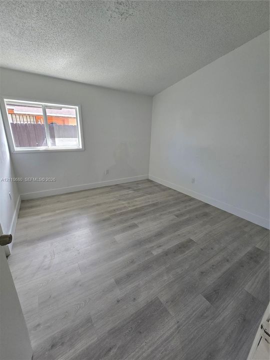 Neutral interior room featuring wood-finish flooring, white walls, and a horizontal window