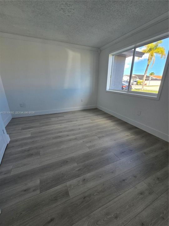Interior space featuring wood-finish flooring, white walls, and a large horizontal sliding window