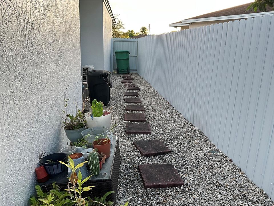 Side yard featuring a gravel path with concrete pavers and a privacy fence