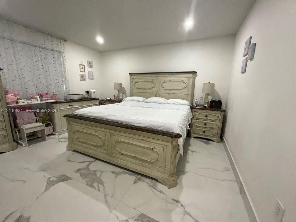 Large-format porcelain tile flooring featuring a marbled finish paired with recessed ceiling lighting